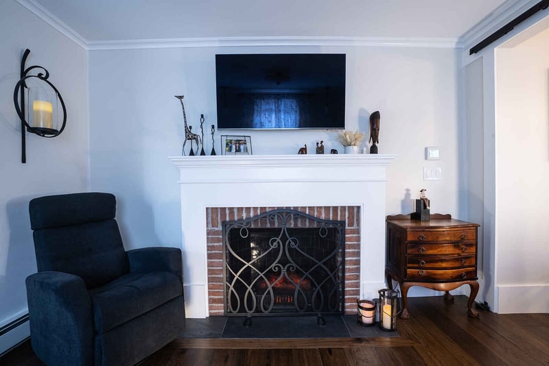 Brick fireplace with white surround and mounted TV above in home remodel by Oxland Builders 